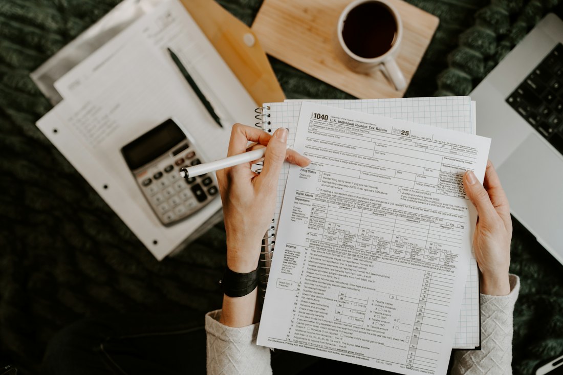 Financial documents being reviewed beside a laptop and calculator
